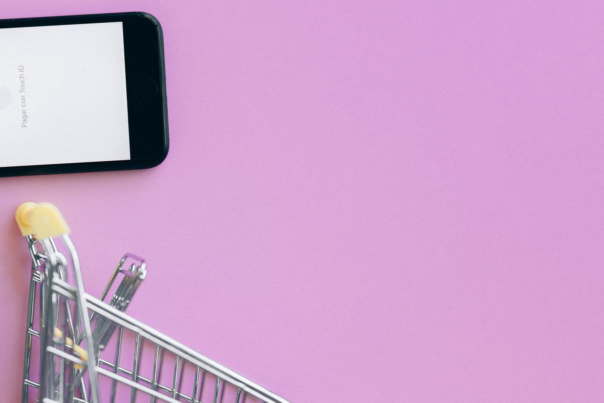 Smartphone, cartes bancaires et mini panier d'achat illustrant l'achat sur mobile dans une boutique en ligne